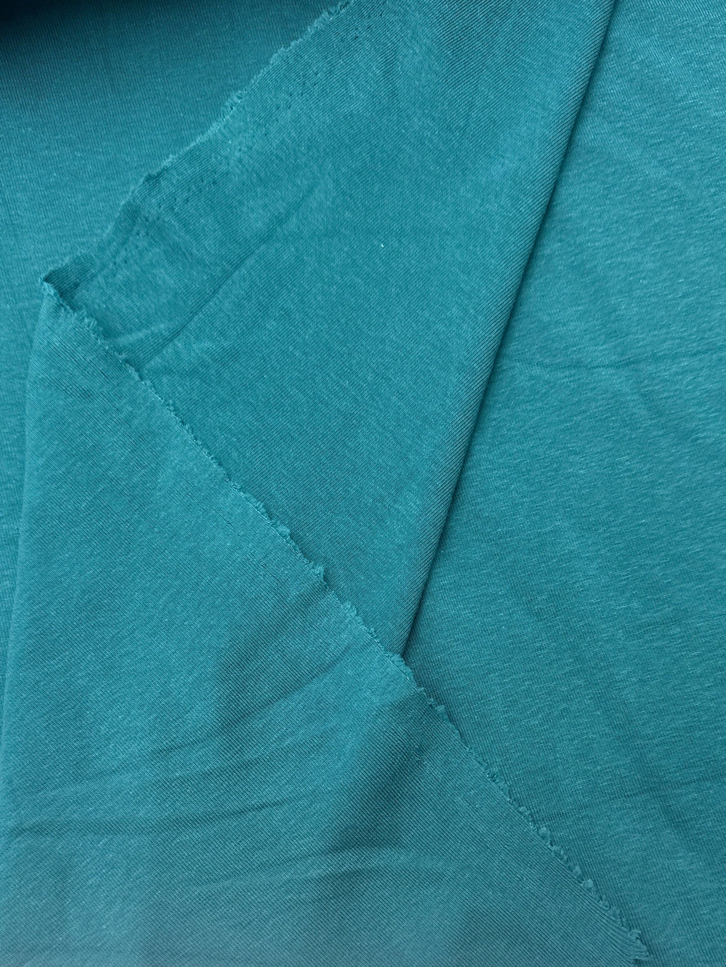 A close-up of teal fabric with visible folds 