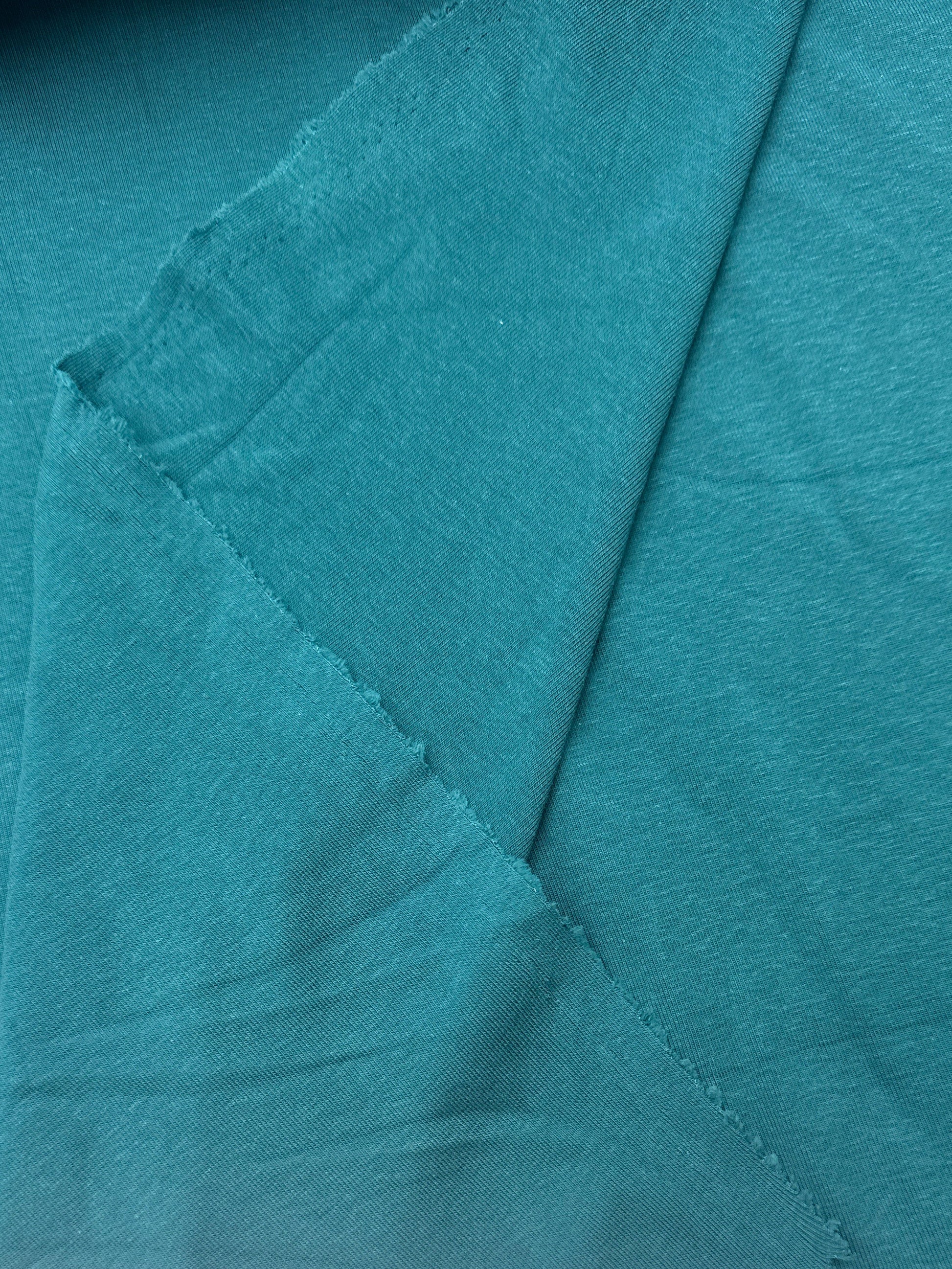 A close-up of teal fabric with visible folds 