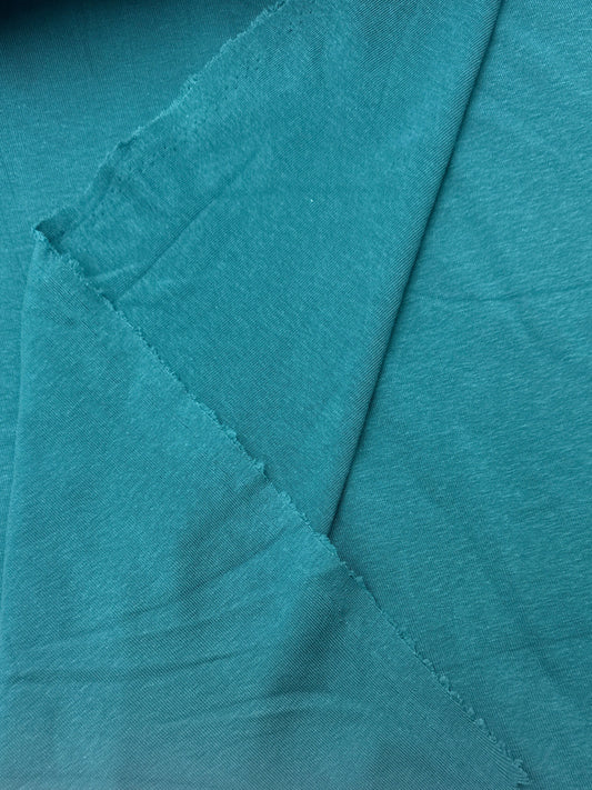 A close-up of teal fabric with visible folds 