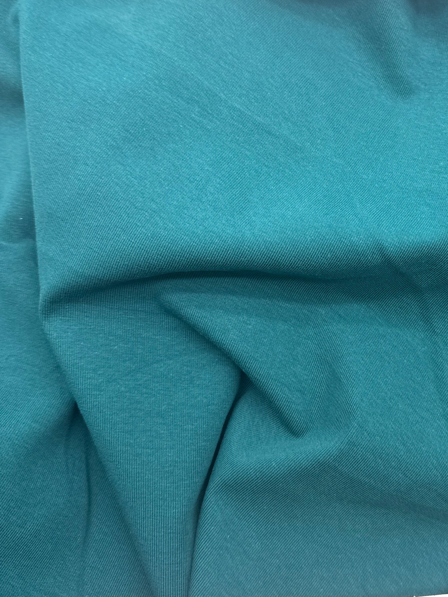 A close-up of teal fabric likely showing material color and texture.