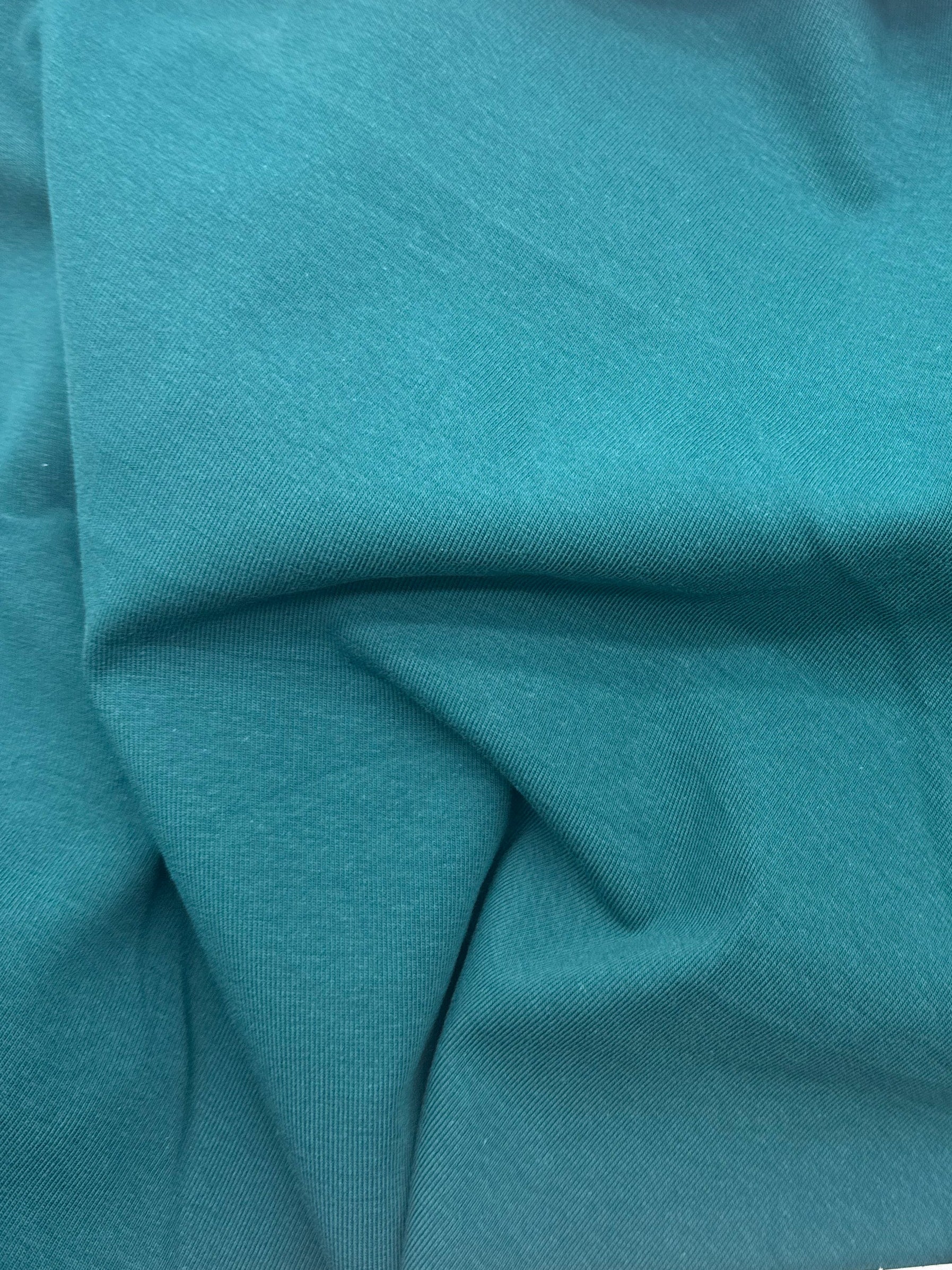 A close-up of teal fabric likely showing material color and texture.